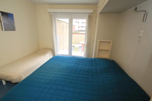 a bedroom with a blue bed and a window at Appartement Sincfala in Knokke-Heist