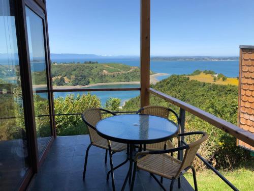 a table and chairs on a balcony with a view of the water at Cabañas Tungulú in Puerto Montt