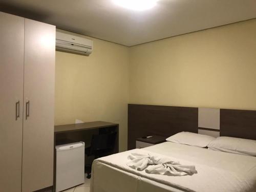 1 dormitorio con cama blanca y escritorio en Hotel Moura, en Brumado