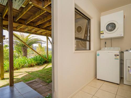 a kitchen with a white refrigerator and a window at At Cathedral Cove - Hahei Holiday Home in Hahei