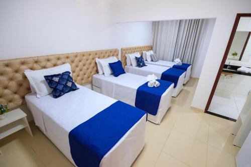 3 camas en una habitación de hotel con azul y blanco en Pousada Tapitanga, en Maragogi