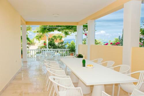 a dining room with a white table and white chairs at Apartments and rooms Gojko - 50 m from the beach in Živogošće