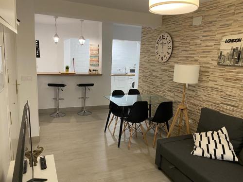 a living room with a table and chairs and a clock at WISH SUITE NIEBLA DE SEVILLA in Seville