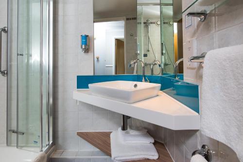 ein Badezimmer mit einem weißen Waschbecken und einer Dusche in der Unterkunft Holiday Inn Express London-Hammersmith, an IHG Hotel in London