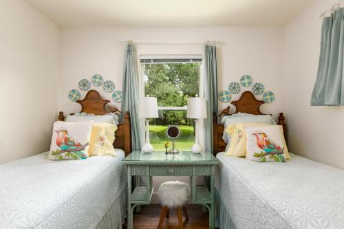 twee bedden in een kamer met een tafel en een raam bij Bear Creek Cottage in Manchaca