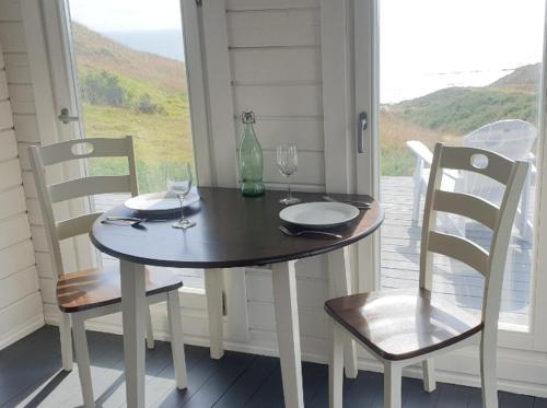 a table and chairs with wine glasses on a porch at SeaView Retreat -Amazing Ocean Views and Outdoor bath in Waiuku