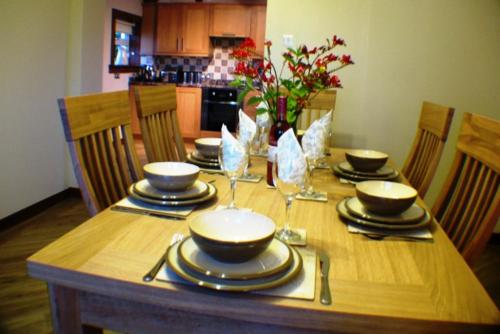 a wooden table with plates and wine glasses on it at Castlemoor Holiday Cottage, Mull of Galloway in Drummore