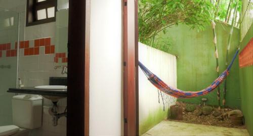 a bathroom with a hammock with a tree on the wall at Pousada Solar D Alcina in Paraty