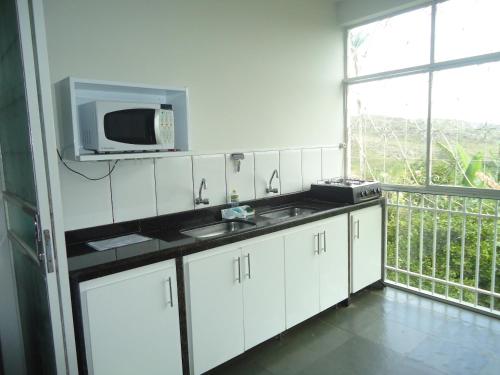 a white kitchen with a sink and a microwave at Hospedagem Solar do Rosário in Diamantina