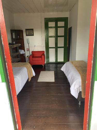 a room with two beds and a red chair at Ecohotel Pinohermoso Reserva Natural in Salento
