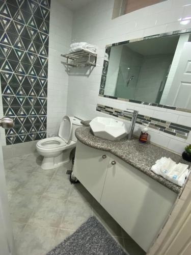 a bathroom with a toilet and a sink and a mirror at Afams Delight Amani Grand Resort Residences 3-5mins from airport in Mactan