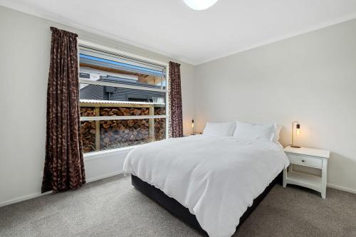 a bedroom with a white bed and a window at Maison de Maude - Lake Hawea Holiday Home in Lake Hawea