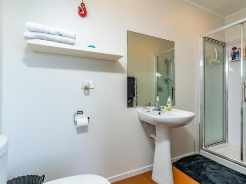 a white bathroom with a sink and a shower at Cheviot's Hideaway - Mangawhai Heads Holiday Home in Mangawhai