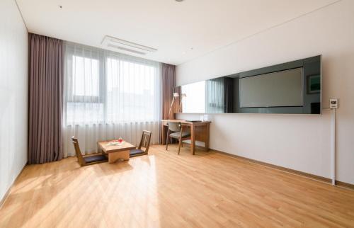 a living room with a tv and a table at Grabel Hotel Jeju in Jeju
