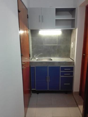 a small kitchen with a sink and blue cabinets at Apart Jujuy monoambiente in San Salvador de Jujuy