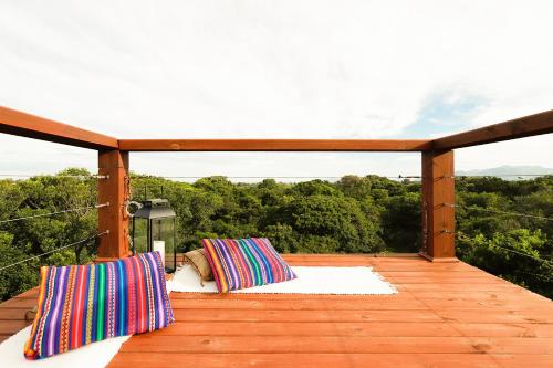 a wooden deck with two pillows on it at Pousada Origin in Guarda do Embaú