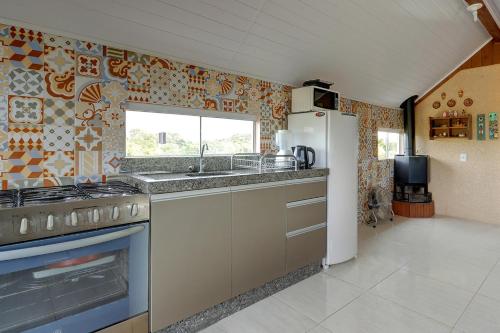 a kitchen with a sink and a refrigerator at Pousada Origin in Guarda do Embaú