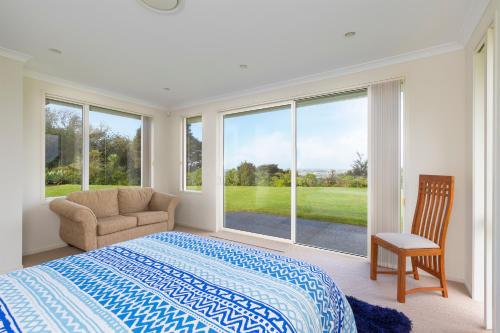 a bedroom with a bed and a chair and a window at Matakana Views - Matakana Holiday Home in Matakana