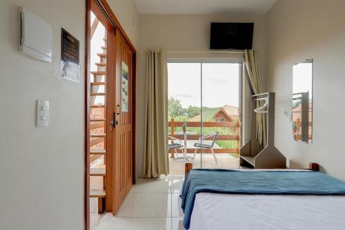 a bedroom with a bed and a view of a balcony at Pousada Origin in Guarda do Embaú