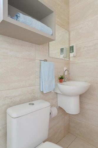 a bathroom with a white toilet and a sink at Pousada Origin in Guarda do Embaú