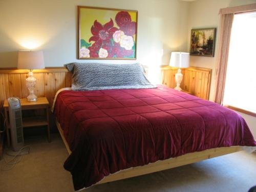 a bedroom with a red bed with two lamps and a window at Higgin's Inn in Powell River