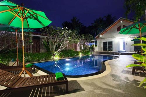 a swimming pool with two benches and an umbrella at Kata Tranquil Villa - SHA Plus in Karon Beach