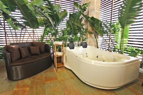 a bath tub in a room with a couch and plants at Luxent Hotel in Manila