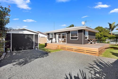 a house with a large deck in front of it at The Black Bach - Mt Maunganui Holiday Home in Mount Maunganui