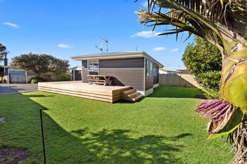 a small house with a deck in a yard at The Black Bach - Mt Maunganui Holiday Home in Mount Maunganui