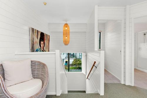 a white room with a chair and a window at Kiwi Kuta with direct beach access -Matarangi Home in Matarangi