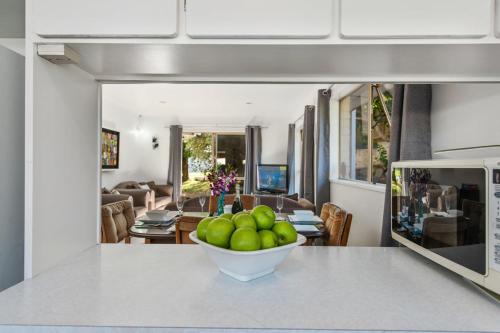 a bowl of apples on a counter in a kitchen at Sandcastles on Tay - Mt Maunganui Holiday Home in Mount Maunganui