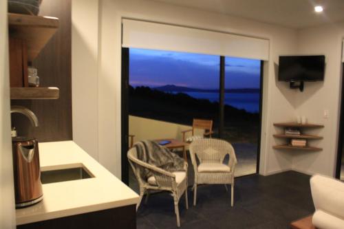 a kitchen with a table and two chairs and a window at Waiheke Island Motel in Ostend