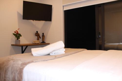a bedroom with a white bed with a television on the wall at Waiheke Island Motel in Ostend