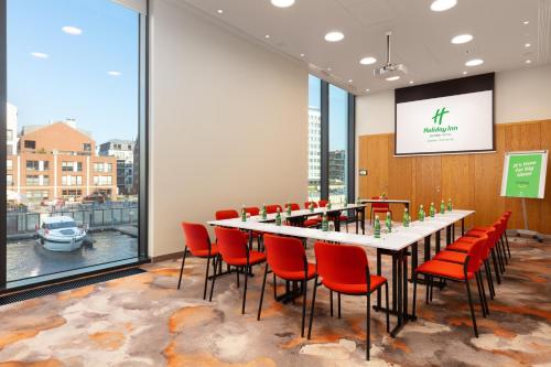 a conference room with a long table and red chairs at Holiday Inn Gdansk - City Centre by IHG in Gdańsk