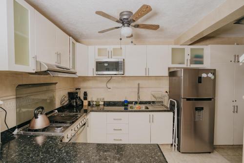 a kitchen with white cabinets and a ceiling fan at DEPA 100 POR CIENTO FAMILIAR ACAPULCO CERCA DEL MAR CON ROFF GARDEN y JACUZZI in Acapulco