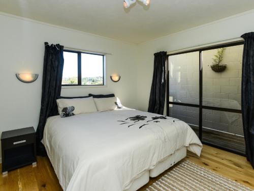 um quarto com uma grande cama branca e um chuveiro em Marine Parade Magic - Napier Holiday Home em Napier