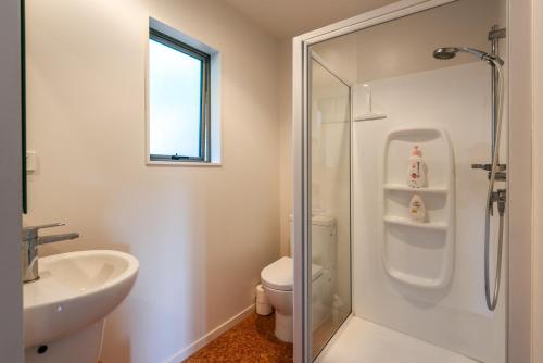 a bathroom with a shower and a toilet and a sink at Treetop Retreat - Onetangi Holiday Home in Onetangi