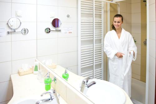 una mujer parada frente a un espejo en un baño en Airport Hotel Budapest, en Vecsés
