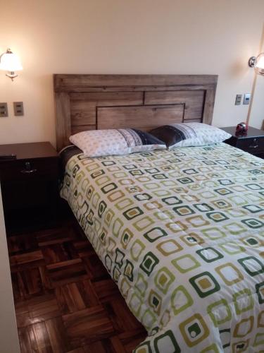 a bedroom with a large bed with a wooden headboard at Hostal Nichkito in Uyuni