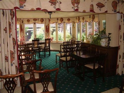 West Lodge Hotel في آيْلسبري: غرفة طعام مع طاولات وكراسي ونوافذ