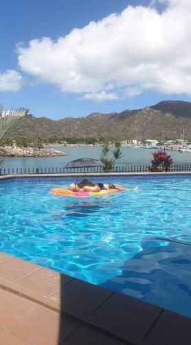 a person laying on a raft in a swimming pool at 1213/146 Sooning street, Nelly Bay, Magnetic Island. Qld 4819. One Bright Point. in Nelly Bay