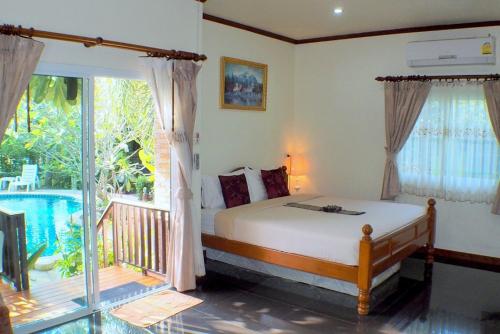 a bedroom with a bed and a balcony with a pool at Pennapa Chalet in Chalong 