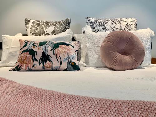 SEAduction Luxury Apartment في نابيير: سرير بمخدات بيضاء وبطانية وردية