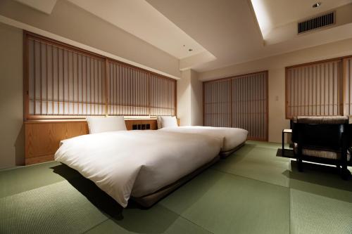 a bedroom with a large white bed and a chair at PROSTYLE RYOKAN TOKYO ASAKUSA in Tokyo