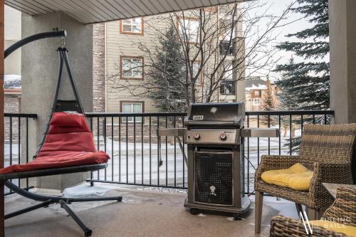 a grill on a balcony with a chair and a chair at Rustic Modern 2 Bed 2 Bath with Lakeview Pool and Hot Tub in Invermere