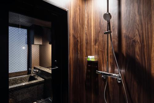 a bathroom with a shower with a wooden wall at PROSTYLE RYOKAN TOKYO ASAKUSA in Tokyo