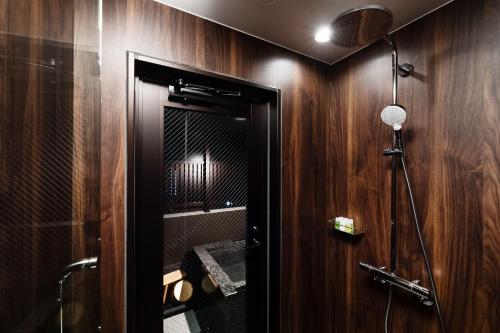 a bathroom with wooden walls and a shower with a mirror at PROSTYLE RYOKAN TOKYO ASAKUSA in Tokyo