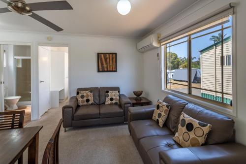 a living room with leather furniture and a large window at Ingenia Holidays Kingscliff in Chinderah