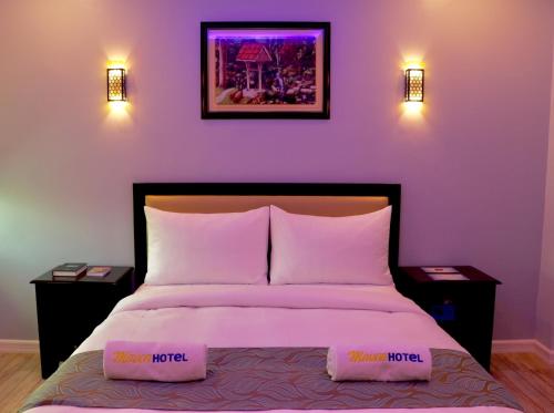 a bedroom with a bed with purple walls and two lights at MAISON HOTEL in Cauayan City