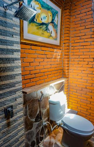 a bathroom with a toilet and a painting on the wall at The Wisma Pulau Merah in Pasanggaran